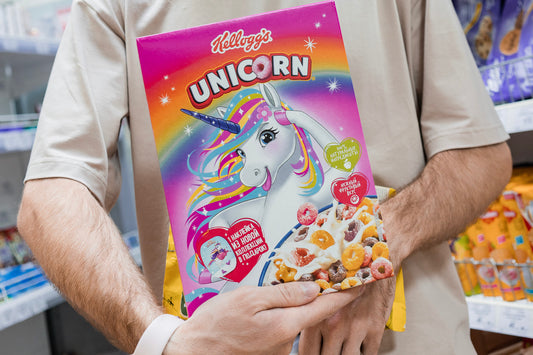 A man in the grocery store holds a box of Kellogg's Unicorn cereal.